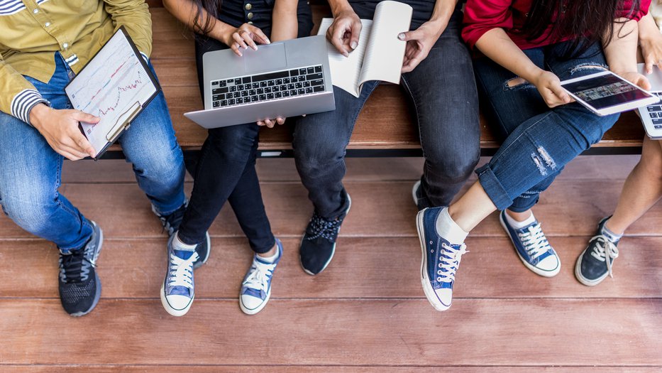 Students sitting together with notepads and laptops