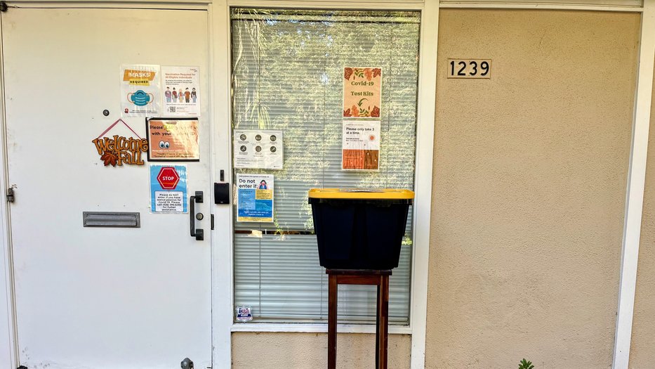Black bin with yellow lid in front of the entrance to the health center